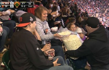 Giants fan shares big bag of popcorn in the stands