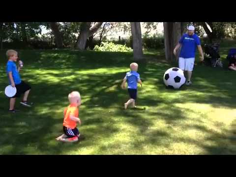 Father kicks large soccer ball knocking down boy