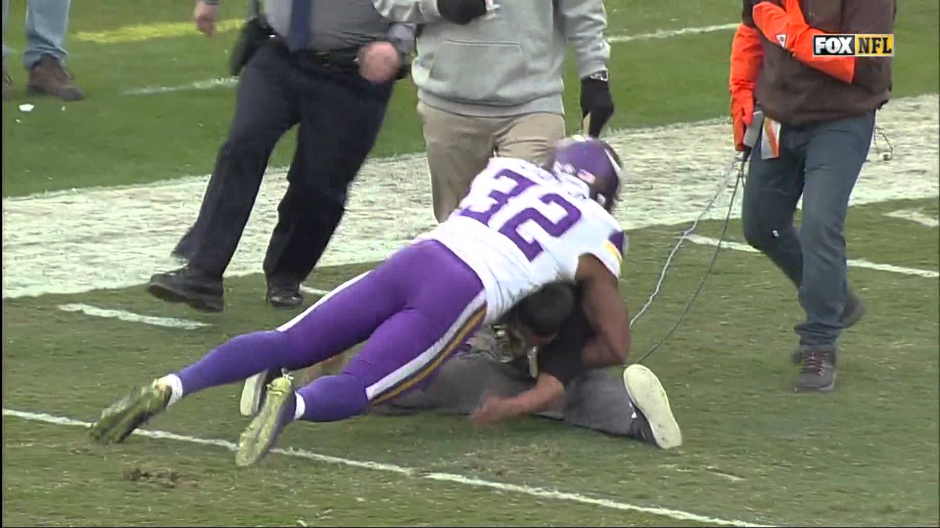 Vikings safety Antone Exum helps to tackle fan on the field