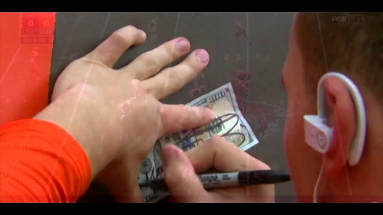 Johnny Manziel signs a $100 dollar bill for a fan